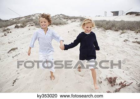 Boy with his sister holding hands and running on sand View Large Photo Image Stock Image - Boy with his sister holding hands and running on sand. Fotosearch
