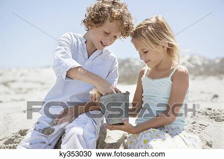 Boy with his sister sitting on sand and playing View Large Photo Image Stock Image - Boy with his sister sitting on sand and playing. Fotosearch