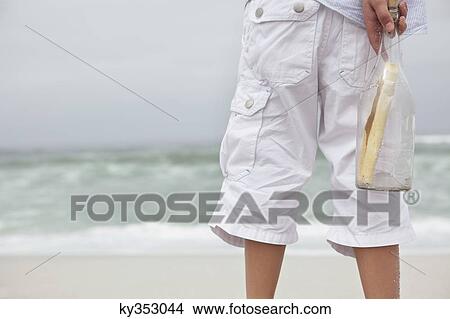 Close-up of boy holding bottle with message on the beach View Large Photo Image Picture - Close-up of boy holding bottle with message on the beach. Fotosearch