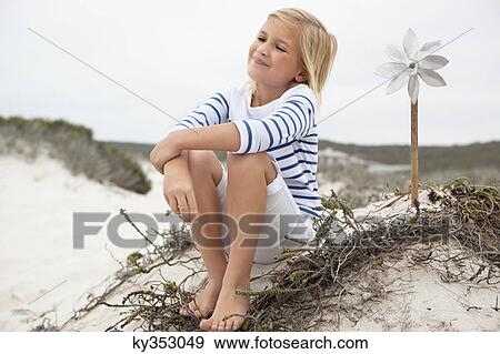 Little girl sitting on sand near pinwheel View Large Photo Image Stock Photo - Little girl sitting on sand near pinwheel. Fotosearch
