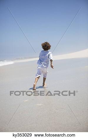 Rear view of a boy running on beach View Large Photo Image Stock Photo - Rear view of a boy running on beach. Fotosearch
