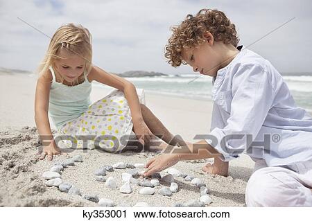 Siblings playing with pebbles on beach View Large Photo Image Stock Image - Siblings playing with pebbles on beach. Fotosearch