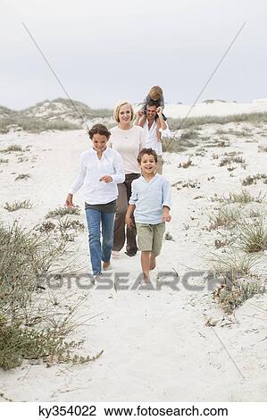 Stock Image - Couple walking on the beach with their children. Fotosearch
