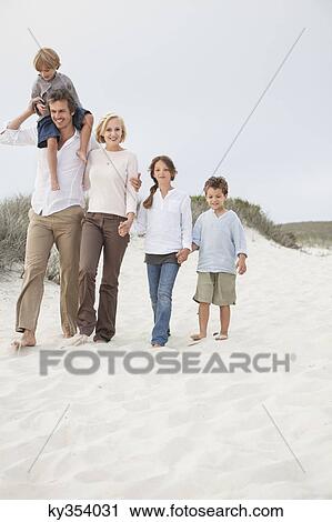 Stock Image - Couple walking on the beach with their children. Fotosearch
