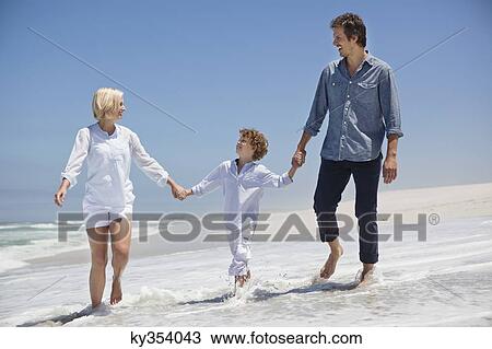 Stock Image - Couple walking on the beach with their son. Fotosearch