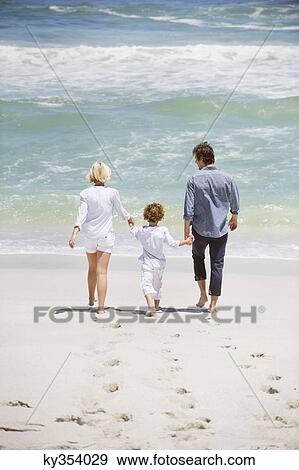 Stock Photo - Couple with their son walking on the beach. Fotosearch