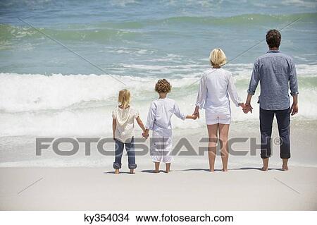 Couple with two children standing on the beach View Large Photo Image Picture - Couple with two children standing on the beach. Fotosearch