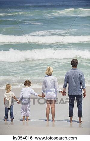 Stock Photograph - Couple with two children standing on the beach. Fotosearch