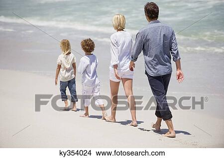 Picture - Couple with two children walking on the beach. Fotosearch