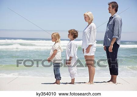 Stock Image - Family standing on the beach. Fotosearch