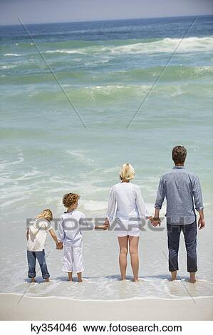 Stock Photograph - Family with two children standing on the beach. Fotosearch