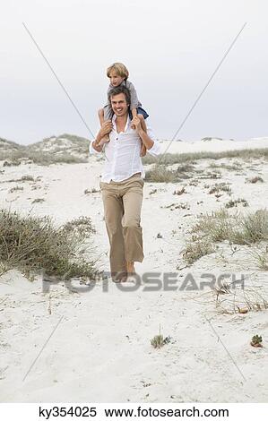 Man carrying his son on his shoulders on the beach View Large Photo Image Stock Photography - Man carrying his son on his shoulders on the beach. Fotosearch