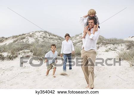 Man walking on sand with their children View Large Photo Image Stock Image - Man walking on sand with their children. Fotosearch
