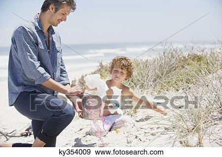 Mid adult man and his son cleaning the beach View Large Photo Image Stock Photo - Mid adult man and his son cleaning the beach. Fotosearch