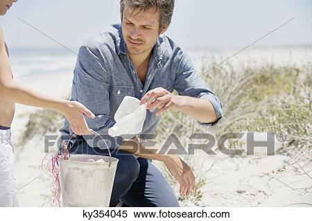 Mid adult man with his son cleaning the beach View Large Photo Image Stock Photography - Mid adult man with his son cleaning the beach. Fotosearch