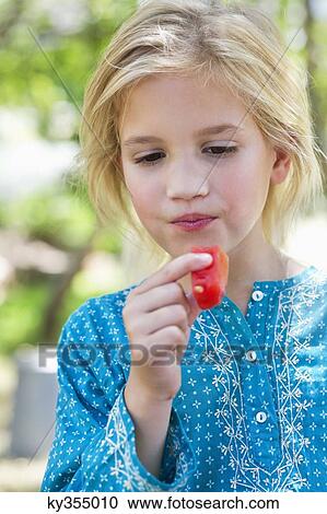 Close-up of a cute girl eating fruit outdoors View Large Photo Image Stock Image - Close-up of a cute girl eating fruit outdoors. Fotosearch
