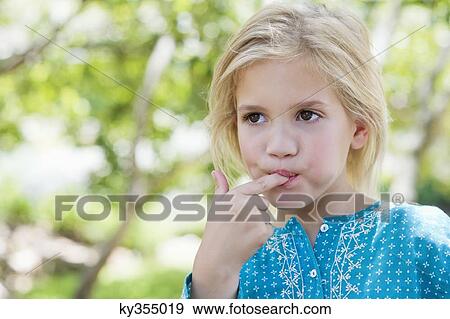 Close-up of a cute girl eating something outdoors View Large Photo Image Stock Photo - Close-up of a cute girl eating something outdoors. Fotosearch