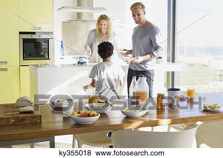 Stock Photo - Couple with their son preparing food in a domestic kitchen. Fotosearch