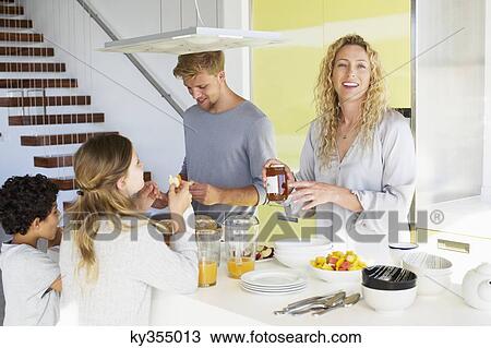 Couple with their two children preparing food at a domestic kitchen View Large Photo Image Stock Image - Couple with their two children preparing food at a domestic kitchen. Fotosearch
