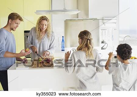 Couple with their two children preparing food at a domestic kitchen View Large Photo Image Stock Image - Couple with their two children preparing food at a domestic kitchen. Fotosearch