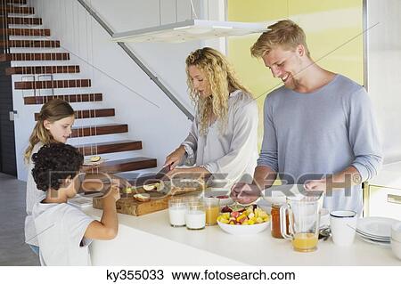 Couple with their two children preparing food at a domestic kitchen View Large Photo Image Stock Image - Couple with their two children preparing food at a domestic kitchen. Fotosearch