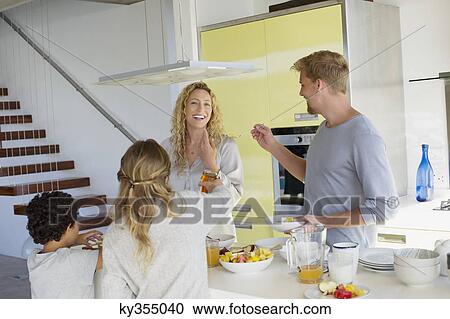 Stock Image - Couple with their two children preparing food at a domestic kitchen. Fotosearch