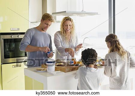 Couple with their two children preparing food at a domestic kitchen View Large Photo Image Stock Image - Couple with their two children preparing food at a domestic kitchen. Fotosearch