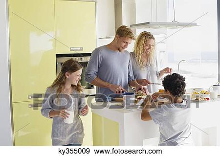 Couple with their two children preparing food at a domestic kitchen View Large Photo Image Stock Photo - Couple with their two children preparing food at a domestic kitchen. Fotosearch