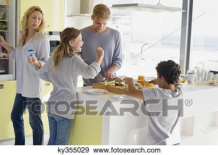 Stock Photo - Couple with their two children preparing food at a domestic kitchen. Fotosearch