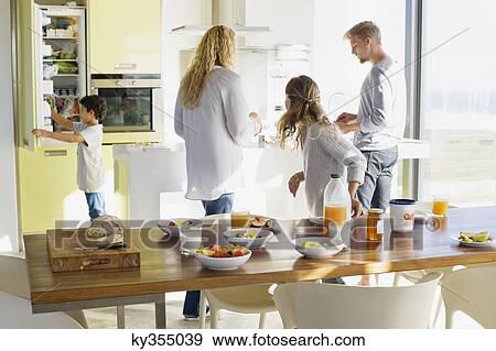 Couple with their two children preparing food at a domestic kitchen View Large Photo Image Stock Photo - Couple with their two children preparing food at a domestic kitchen. Fotosearch