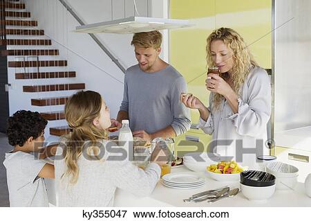 Couple with their two children preparing food at a domestic kitchen View Large Photo Image Stock Photo - Couple with their two children preparing food at a domestic kitchen. Fotosearch