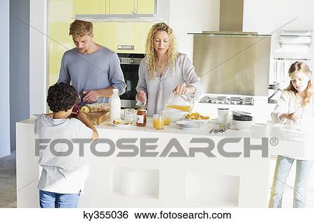 Couple with their two children preparing food at a domestic kitchen View Large Photo Image Stock Photograph - Couple with their two children preparing food at a domestic kitchen. Fotosearch