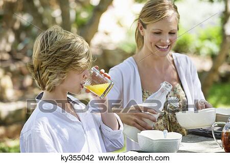 Mother having food with her son outdoors View Large Photo Image Stock Image - Mother having food with her son outdoors. Fotosearch