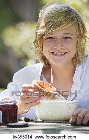 Portrait of a little boy eating bread with jam outdoors View Large Photo Image Picture - Portrait of a little boy eating bread with jam outdoors. Fotosearch