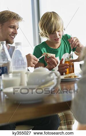 Stock Photo - Teenage boy having breakfast with his parents. Fotosearch