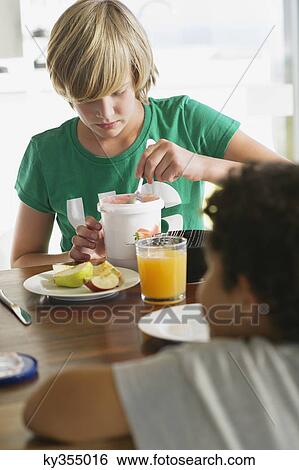 Teenage boy having breakfast with his brother sitting in front of him View Large Photo Image Stock Photograph - Teenage boy having breakfast with his brother sitting in front of him. Fotosearch