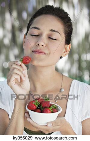 Beautiful young woman holding a bowl of strawberries with her eyes closed View Large Photo Image Stock Photo - Beautiful young woman holding a bowl of strawberries with her eyes closed. Fotosearch