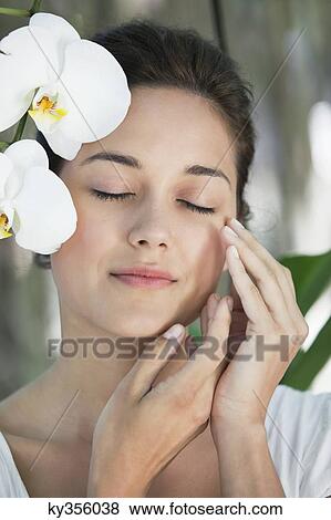 Beautiful young woman standing by the flower with her eyes closed View Large Photo Image Stock Photo - Beautiful young woman standing by the flower with her eyes closed. Fotosearch