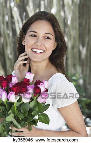 Happy young woman holding bunch of colorful roses View Large Photo Image Stock Photograph - Happy young woman holding bunch of colorful roses. Fotosearch