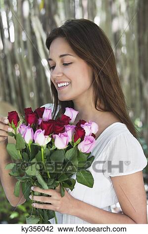Happy young woman looking at bunch of colorful roses View Large Photo Image Stock Image - Happy young woman looking at bunch of colorful roses. Fotosearch