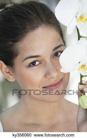 Portrait of a beautiful young woman holding flowers View Large Photo Image Stock Image - Portrait of a beautiful young woman holding flowers. Fotosearch