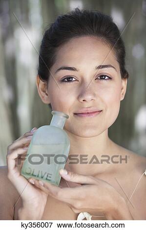 Portrait of a beautiful young woman holding bottle of olive oil View Large Photo Image Stock Photo - Portrait of a beautiful young woman holding bottle of olive oil. Fotosearch
