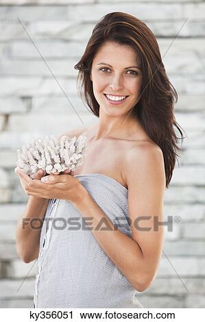 Stock Image - Portrait of a woman holding a flower and smiling. Fotosearch