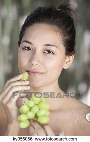 Portrait of a young woman eating grapes View Large Photo Image Stock Photograph - Portrait of a young woman eating grapes. Fotosearch