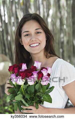 Portrait of a young woman holding bunch of colorful roses View Large Photo Image Picture - Portrait of a young woman holding bunch of colorful roses. Fotosearch