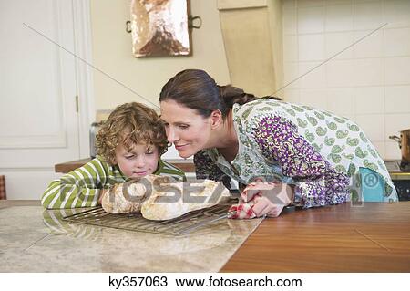 Stock Image - Cute little boy and mother smelling baked bread. Fotosearch
