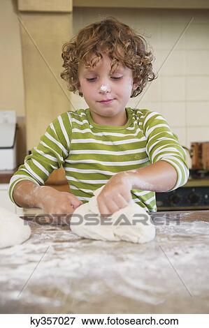 Cute little boy kneading dough at kitchen View Large Photo Image Stock Photo - Cute little boy kneading dough at kitchen. Fotosearch