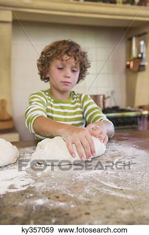 Cute little boy kneading dough at kitchen View Large Photo Image Stock Photo - Cute little boy kneading dough at kitchen. Fotosearch