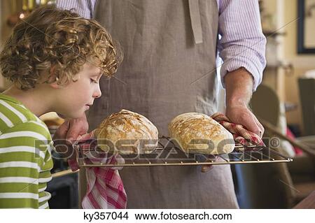 Picture - Cute little boy smelling baked bread in father's hand. Fotosearch