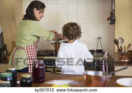 Stock Image - Grandmother and little boy cooking food together at home. Fotosearch